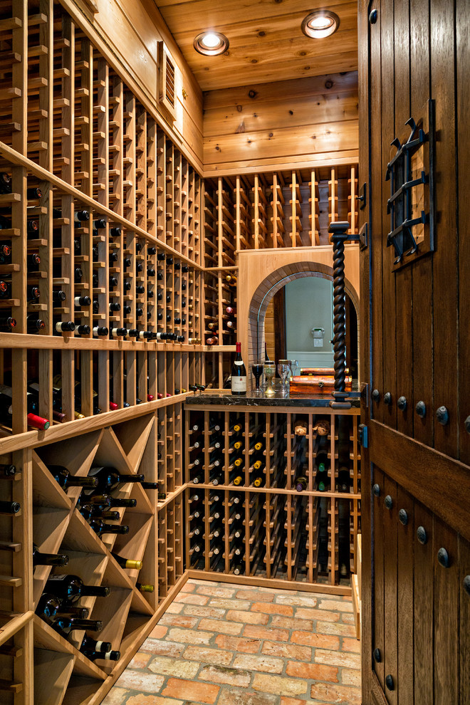 This is an example of a traditional wine cellar in Miami with brick floors, storage racks and orange floor.