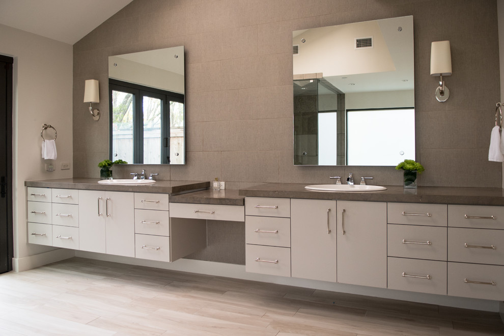 Inspiration for a mid-sized transitional master gray tile and cement tile light wood floor and beige floor drop-in bathtub remodel in Dallas with flat-panel cabinets, gray cabinets, gray walls, a drop-in sink, concrete countertops and a hinged shower door