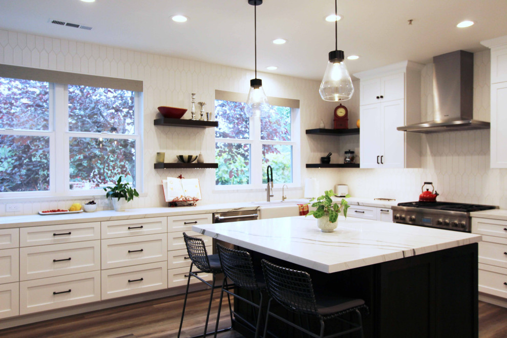 Open concept kitchen - large transitional l-shaped vinyl floor and brown floor open concept kitchen idea with a farmhouse sink, shaker cabinets, white cabinets, quartz countertops, white backsplash, ceramic backsplash, stainless steel appliances, an island and white countertops