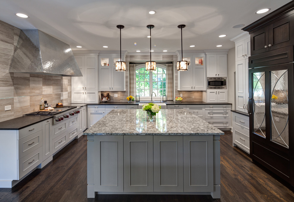 Inspiration for a transitional l-shaped kitchen remodel in Chicago with a farmhouse sink, stainless steel appliances, beige backsplash and stone tile backsplash