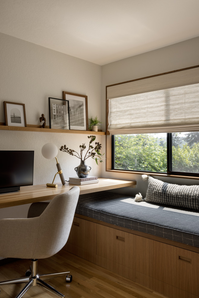 Study room - mid-sized contemporary built-in desk medium tone wood floor study room idea in Seattle with beige walls and no fireplace
