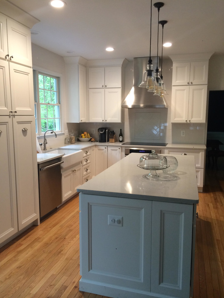 Inspiration for a mid-sized transitional l-shaped medium tone wood floor and brown floor open concept kitchen remodel in DC Metro with a farmhouse sink, shaker cabinets, white cabinets, quartz countertops, white backsplash, subway tile backsplash, stainless steel appliances and an island