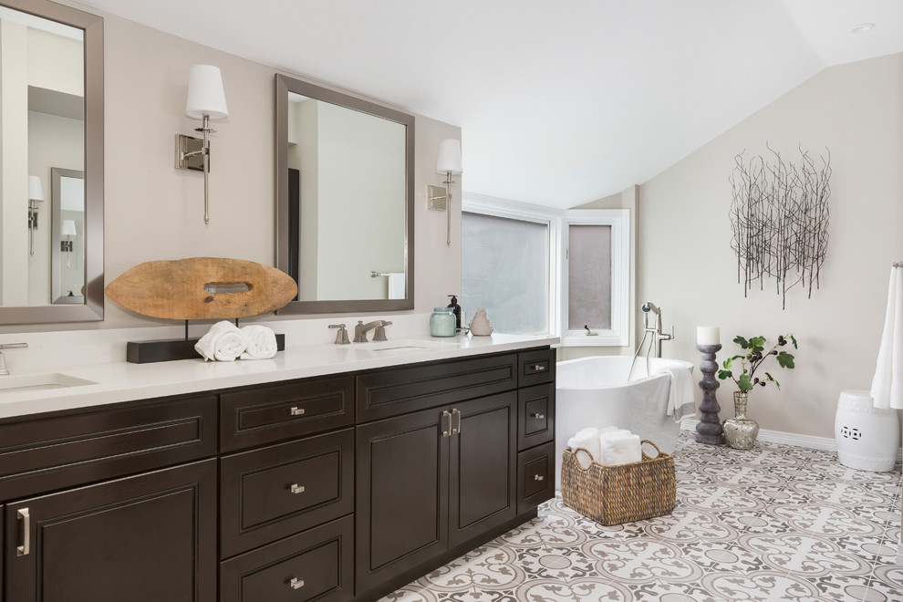 Photo of a mid-sized transitional master bathroom in Denver with raised-panel cabinets, dark wood cabinets, a freestanding tub, grey walls, an undermount sink, engineered quartz benchtops, grey floor, white benchtops and cement tiles.
