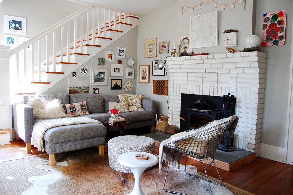 Design ideas for a scandinavian living room in New York with grey walls and a brick fireplace surround.