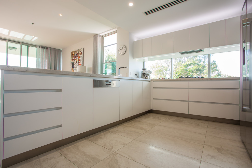 Photo of a large u-shaped open plan kitchen in Brisbane with a double-bowl sink, recessed-panel cabinets, white cabinets, solid surface benchtops, stainless steel appliances, porcelain floors, multiple islands, brown floor and brown benchtop.
