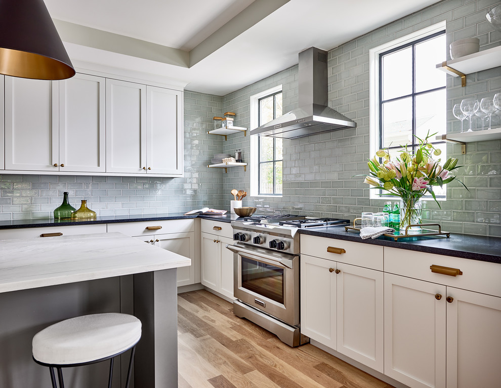 Design ideas for a transitional kitchen in Charlotte with shaker cabinets, white cabinets, grey splashback, subway tile splashback, stainless steel appliances, medium hardwood floors, with island and beige floor.