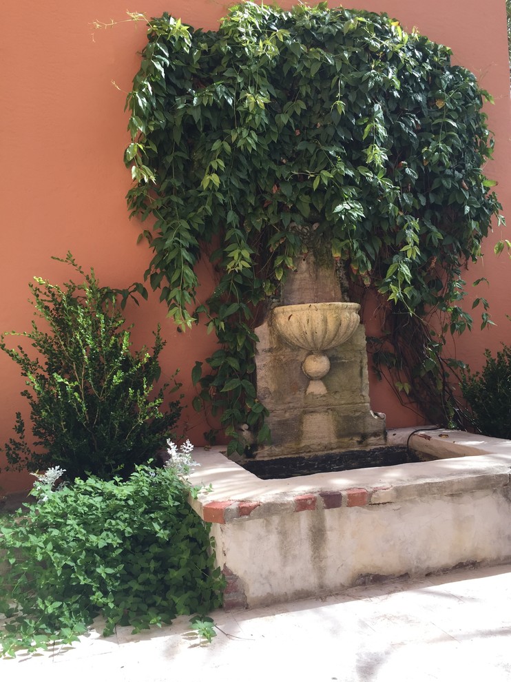 Photo of a mediterranean courtyard patio in Denver with a water feature, natural stone pavers and no cover.
