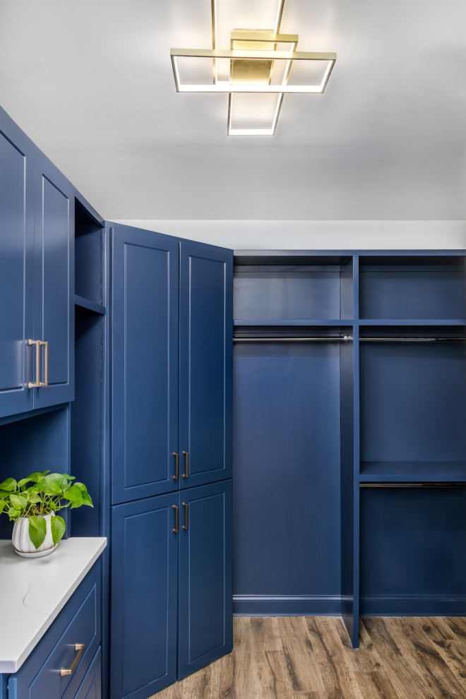 Inspiration for a large transitional gender-neutral storage and wardrobe in Atlanta with raised-panel cabinets, blue cabinets, vinyl floors and brown floor.
