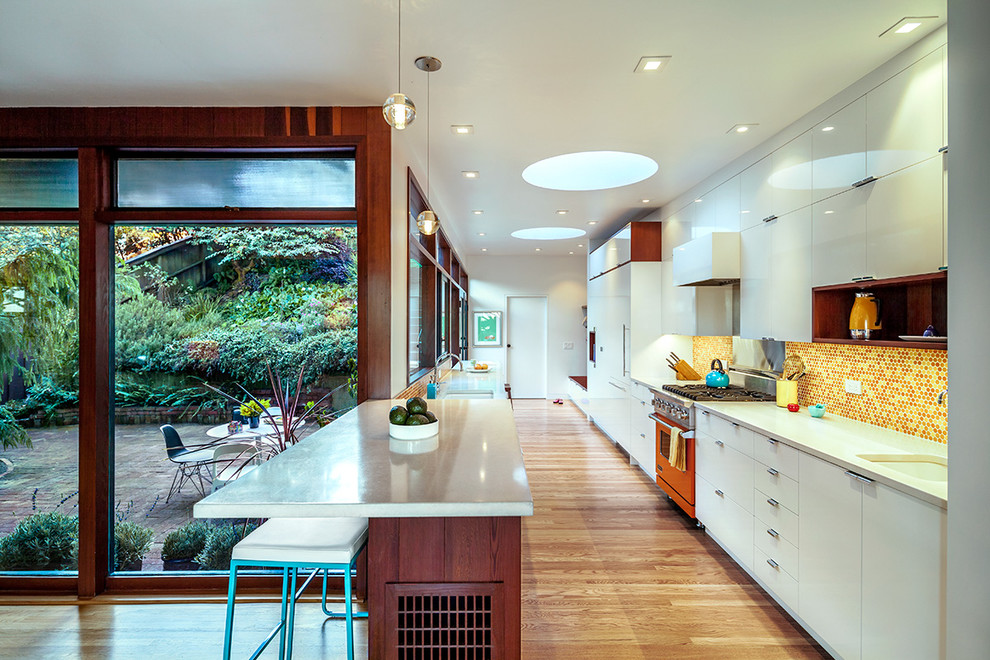 Inspiration for a midcentury galley separate kitchen in San Francisco with flat-panel cabinets, white cabinets, multi-coloured splashback, mosaic tile splashback and coloured appliances.