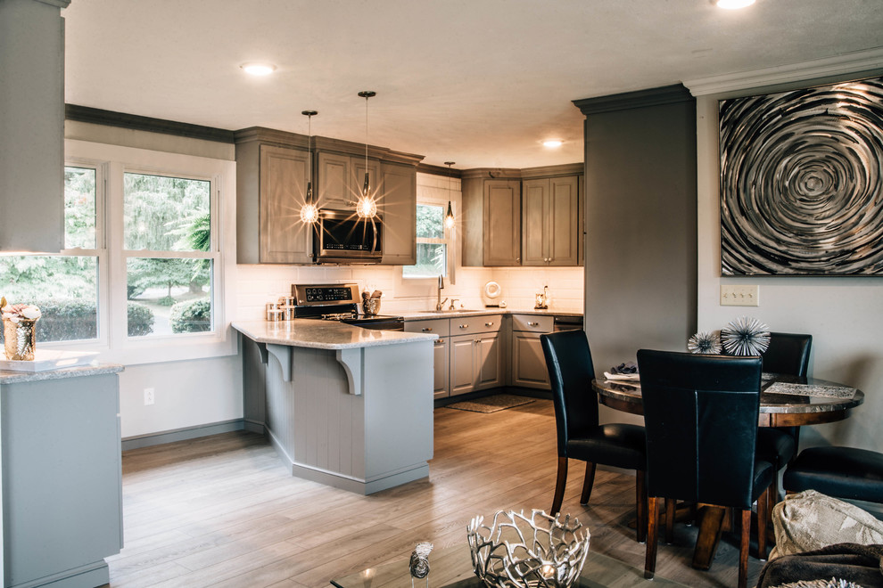 Example of a mid-sized transitional u-shaped medium tone wood floor and brown floor eat-in kitchen design with a double-bowl sink, raised-panel cabinets, gray cabinets, granite countertops, white backsplash, ceramic backsplash, stainless steel appliances, a peninsula and gray countertops