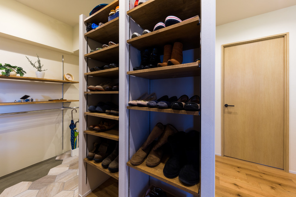 Design ideas for a mid-sized country gender-neutral walk-in wardrobe in Osaka with open cabinets, dark hardwood floors and brown floor.