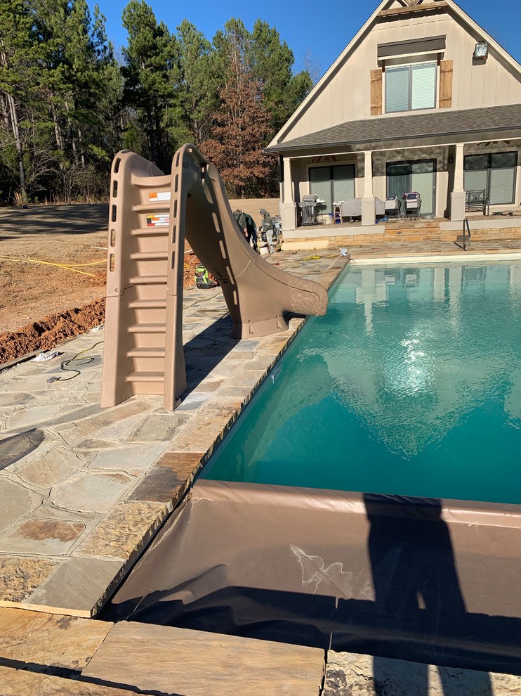 Inspiration for a large modern backyard custom-shaped natural pool in Other with a pool house and natural stone pavers.