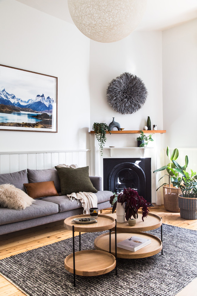 This is an example of a scandinavian open concept living room in Melbourne with white walls, light hardwood floors, a standard fireplace, a metal fireplace surround and brown floor.