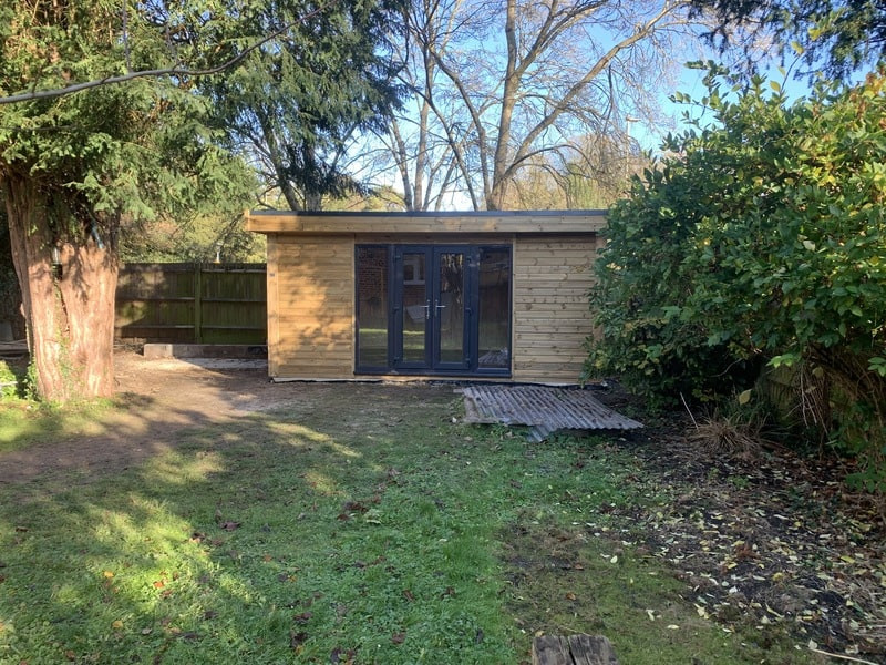 Large contemporary home studio in Hampshire with beige walls, laminate floors, a freestanding desk, brown floors, a timber clad ceiling and tongue and groove walls.