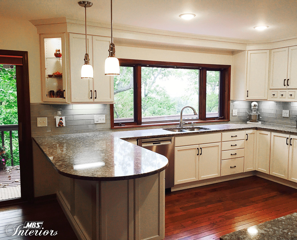 Inspiration for a transitional u-shaped enclosed kitchen remodel with an undermount sink, flat-panel cabinets, white cabinets, quartz countertops, gray backsplash, subway tile backsplash, stainless steel appliances and a peninsula