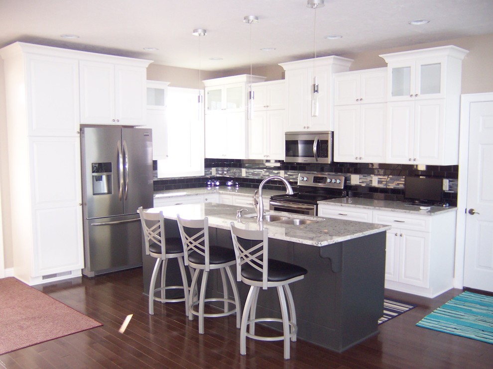 Inspiration for a transitional l-shaped kitchen remodel with a double-bowl sink, raised-panel cabinets, white cabinets, granite countertops, stainless steel appliances and an island