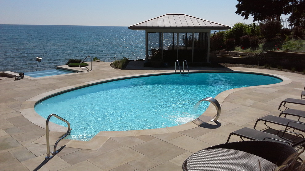 Design ideas for a mid-sized transitional backyard kidney-shaped pool in Chicago with a hot tub and concrete pavers.