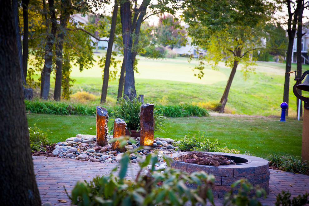 This is an example of a mid-sized traditional front yard full sun garden for fall in Kansas City with a fire feature and natural stone pavers.