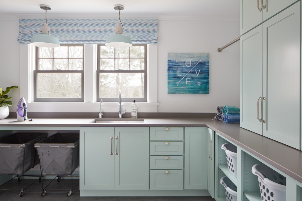 This is an example of a large transitional u-shaped dedicated laundry room in Boston with an undermount sink, turquoise cabinets, quartz benchtops, white walls, ceramic floors, a stacked washer and dryer, grey floor and grey benchtop.