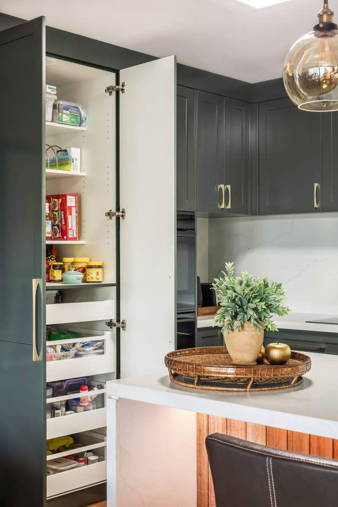 Example of a large transitional l-shaped medium tone wood floor and multicolored floor eat-in kitchen design in Sydney with a drop-in sink, shaker cabinets, green cabinets, quartz countertops, white backsplash, quartz backsplash, black appliances, an island and white countertops