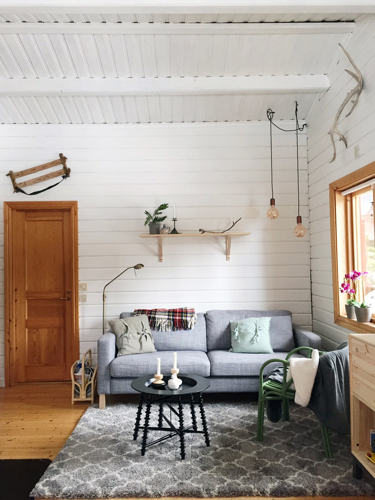 This is an example of a mid-sized country open concept family room in Stockholm with white walls, light hardwood floors, no fireplace and no tv.