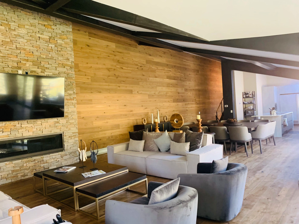 Immagine di un ampio soggiorno moderno con pareti marroni, cornice del camino in pietra ricostruita, pavimento marrone, soffitto a volta e pareti in legno