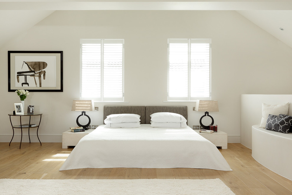 Contemporary bedroom in London with white walls and light hardwood floors.