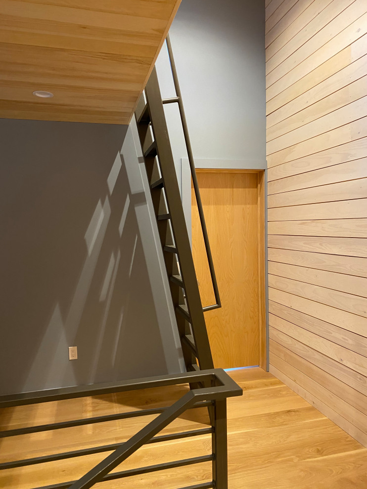 Cette image montre un petit escalier droit minimaliste en bois avec des marches en métal, des contremarches en métal et un garde-corps en métal.