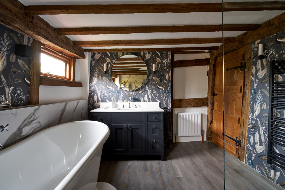 Inspiration for a country bathroom in Sussex with shaker cabinets, black cabinets, a freestanding tub, multi-coloured walls, an undermount sink, grey floor, white benchtops, a single vanity, exposed beam and wallpaper.
