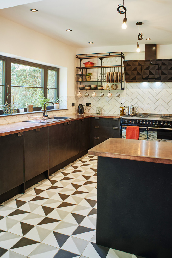 Mid-sized modern u-shaped eat-in kitchen in Sussex with a drop-in sink, flat-panel cabinets, black cabinets, copper benchtops, white splashback, subway tile splashback, black appliances, ceramic floors, a peninsula and multi-coloured floor.