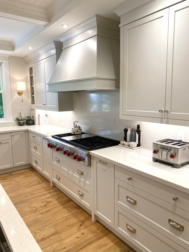 Open concept kitchen - mid-sized transitional u-shaped medium tone wood floor, brown floor and coffered ceiling open concept kitchen idea in Toronto with an undermount sink, shaker cabinets, quartz countertops, white backsplash, quartz backsplash, paneled appliances, an island and white countertops