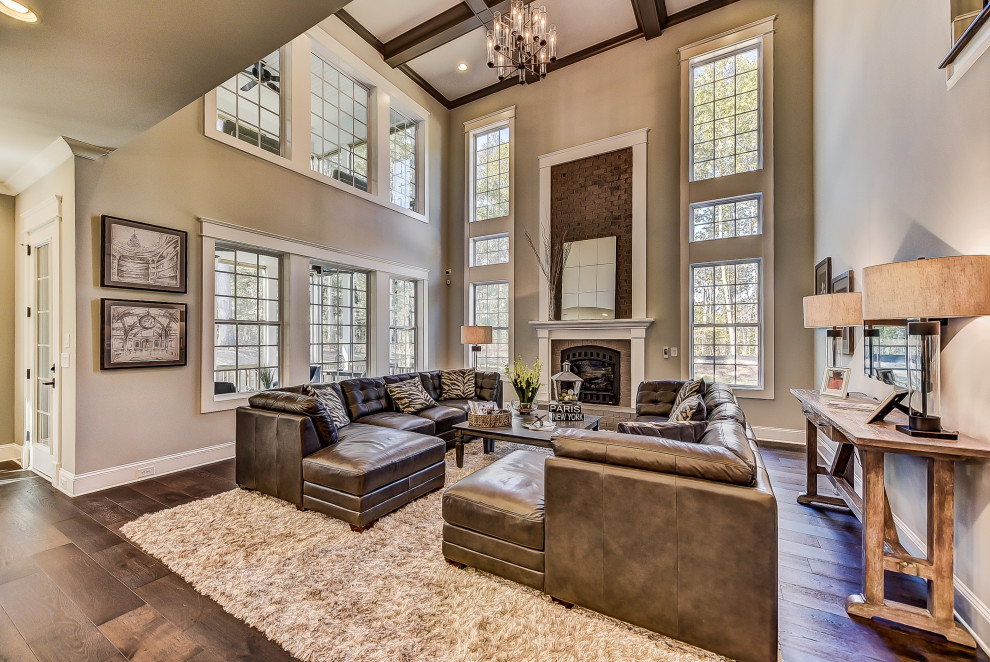Inspiration for an expansive transitional open concept living room in Charlotte with beige walls, medium hardwood floors, a standard fireplace, a brick fireplace surround and coffered.
