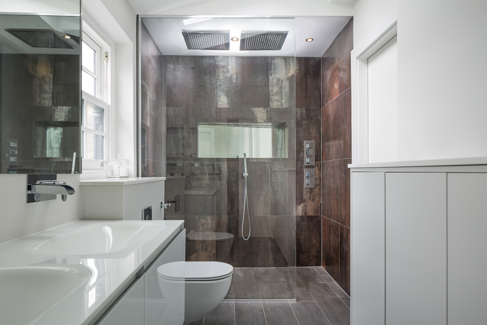 Design ideas for a large contemporary master bathroom in London with flat-panel cabinets, white cabinets, a wall-mount toilet, porcelain tile, white walls, porcelain floors, an integrated sink, solid surface benchtops and a curbless shower.