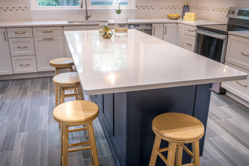 Large transitional u-shaped porcelain tile and gray floor open concept kitchen photo in Chicago with an undermount sink, shaker cabinets, white cabinets, quartz countertops, white backsplash, ceramic backsplash, stainless steel appliances, an island and white countertops