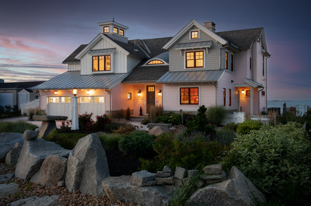 Large beach style pink two-story wood and shingle exterior home photo in Boston with a mixed material roof and a gray roof