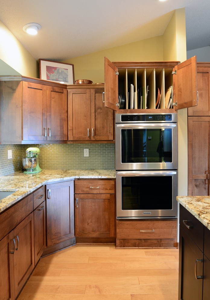 Inspiration for a mid-sized transitional u-shaped light wood floor open concept kitchen remodel with an undermount sink, shaker cabinets, medium tone wood cabinets, granite countertops, glass tile backsplash, stainless steel appliances and an island