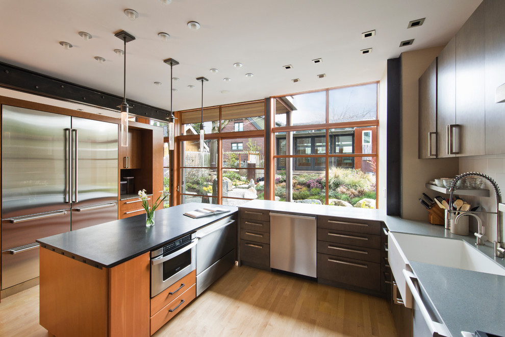 Design ideas for a mid-sized modern u-shaped separate kitchen in Seattle with a farmhouse sink, flat-panel cabinets, medium wood cabinets, white splashback, subway tile splashback, stainless steel appliances, light hardwood floors and with island.