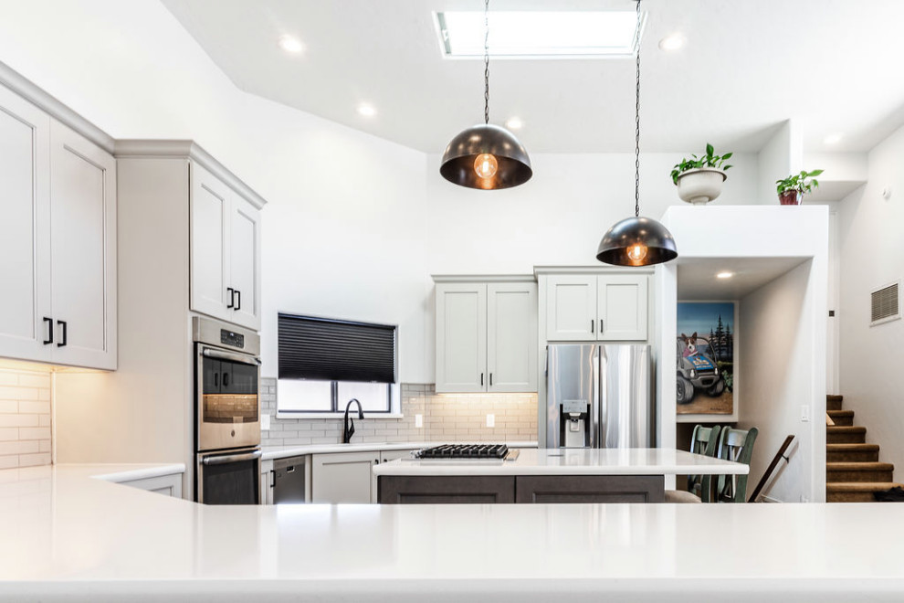 Large transitional u-shaped vinyl floor and gray floor eat-in kitchen photo with an undermount sink, shaker cabinets, gray cabinets, quartzite countertops, green backsplash, subway tile backsplash, stainless steel appliances, an island and white countertops