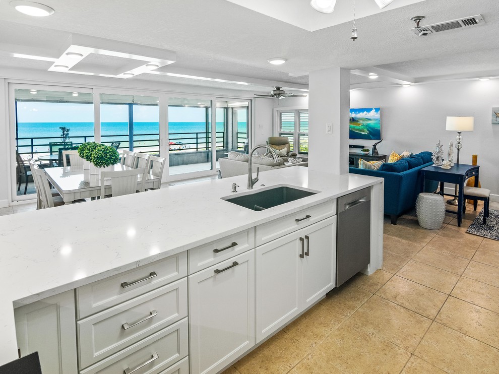 Photo of a mid-sized beach style u-shaped eat-in kitchen in Tampa with an undermount sink, shaker cabinets, white cabinets, quartzite benchtops, grey splashback, ceramic splashback, stainless steel appliances, porcelain floors, a peninsula, beige floor and white benchtop.