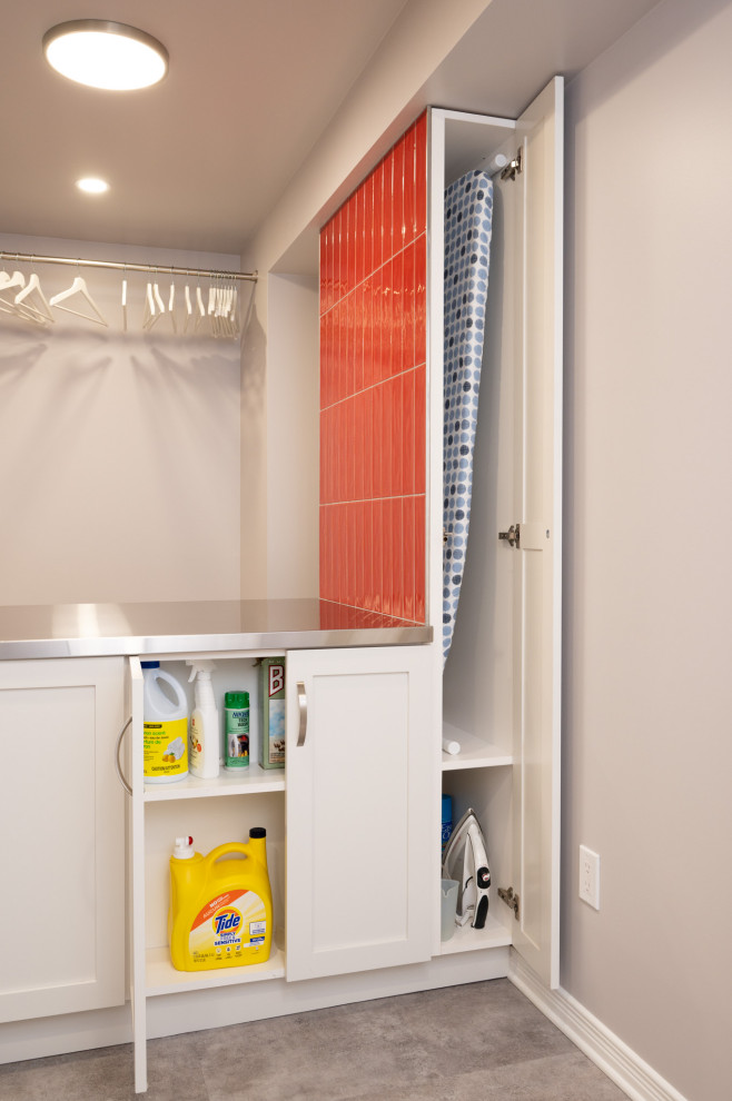 オタワにあるお手頃価格の中くらいなコンテンポラリースタイルのおしゃれな洗濯室 (スロップシンク、シェーカースタイル扉のキャビネット、白いキャビネット、ステンレスカウンター、赤いキッチンパネル、サブウェイタイルのキッチンパネル、白い壁、クッションフロア、左右配置の洗濯機・乾燥機、グレーの床) の写真