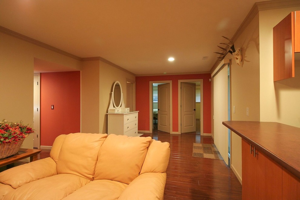 Inspiration for a mid-sized transitional underground medium tone wood floor and brown floor basement remodel in Vancouver with orange walls, a standard fireplace and a stone fireplace