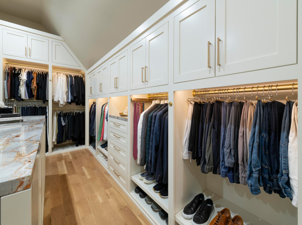 Foto de armario vestidor unisex y abovedado grande con armarios estilo shaker, puertas de armario blancas, suelo de madera clara y suelo marrón