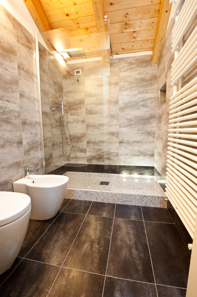 This is an example of a mid-sized modern 3/4 bathroom in Milan with beige cabinets, a double shower, a two-piece toilet, gray tile, porcelain tile, grey walls, porcelain floors, a vessel sink and wood benchtops.