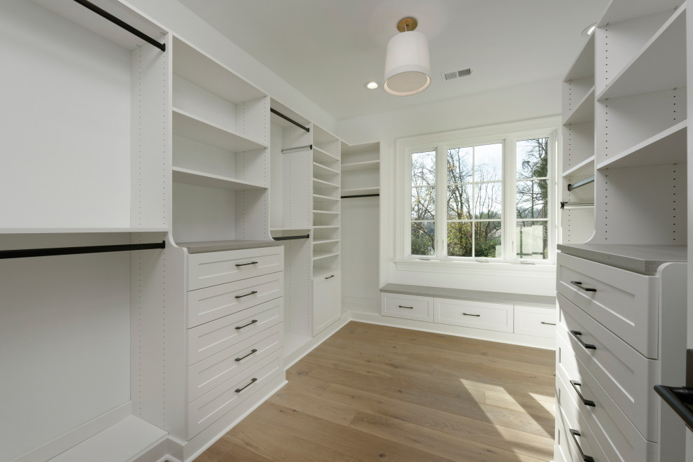 Large arts and crafts gender-neutral storage and wardrobe in Other with beaded inset cabinets, white cabinets, medium hardwood floors, brown floor and vaulted.