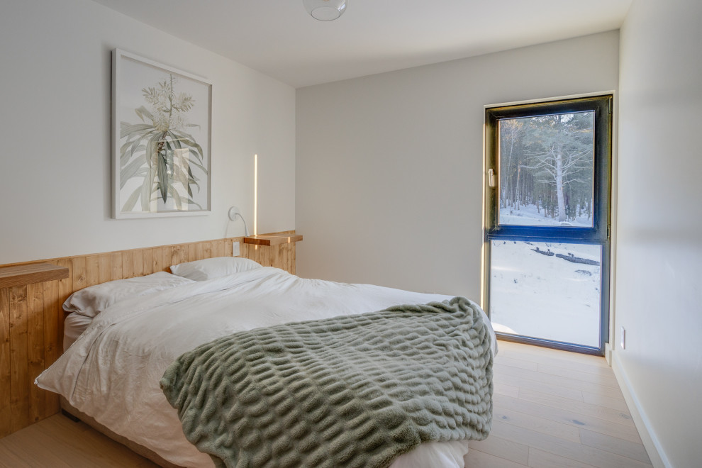 Idée de décoration pour une chambre d'amis nordique de taille moyenne avec parquet clair et du lambris.