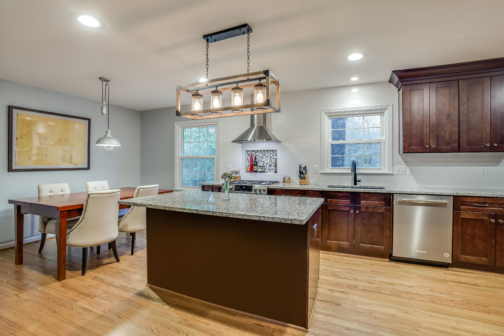 Eat-in kitchen - mid-sized transitional l-shaped light wood floor and yellow floor eat-in kitchen idea in Birmingham with a double-bowl sink, shaker cabinets, dark wood cabinets, granite countertops, white backsplash, subway tile backsplash, stainless steel appliances, an island and gray countertops