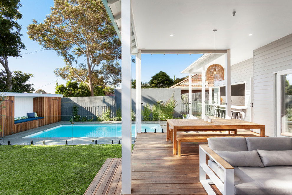 Photo of a large contemporary backyard and ground level deck in Melbourne with a roof extension.