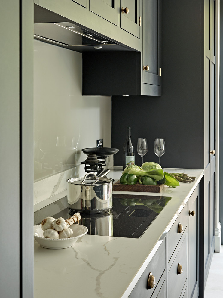Inspiration for a large transitional eat-in kitchen in London with shaker cabinets, black cabinets, solid surface benchtops, grey splashback, porcelain floors, with island and grey floor.