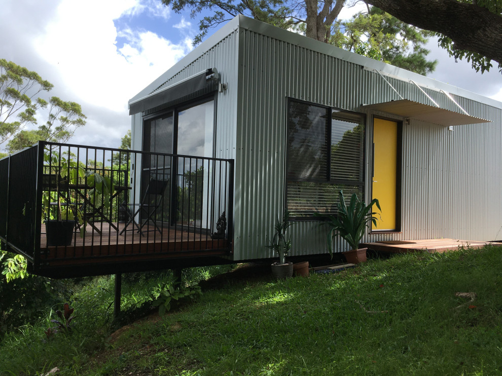 Kleines, Einstöckiges Maritimes Einfamilienhaus mit Metallfassade, grauer Fassadenfarbe, Flachdach, Blechdach und weißem Dach in Sunshine Coast