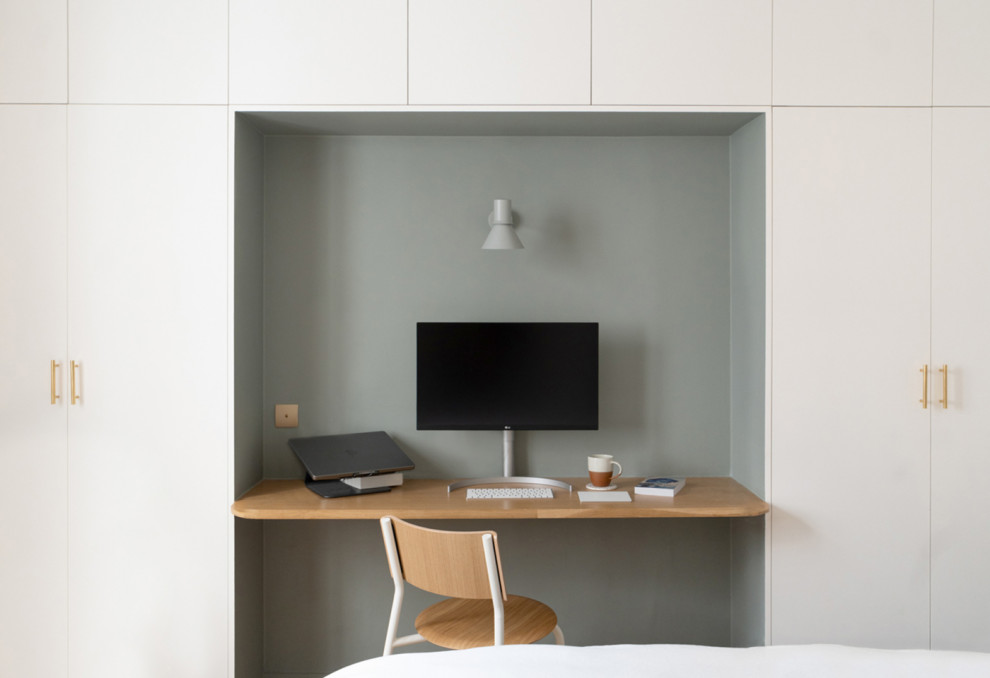 Inredning av ett minimalistiskt arbetsrum, med ett bibliotek, gröna väggar och ett inbyggt skrivbord